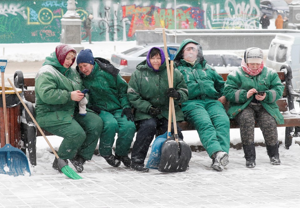 Kiyev kommunal xizmatlari xodimlari qor tozalash ishlaridan so‘ng dam olmoqda.