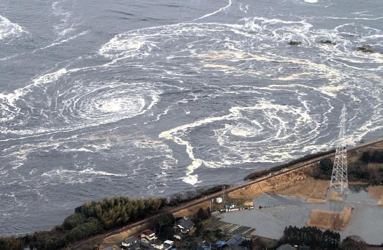 Фукусима префектурасидаги Иваки шаҳрида цунами ва зилзиладан сўнг ҳосил бўлган гирдоблар. 2011 йил, 11 март.