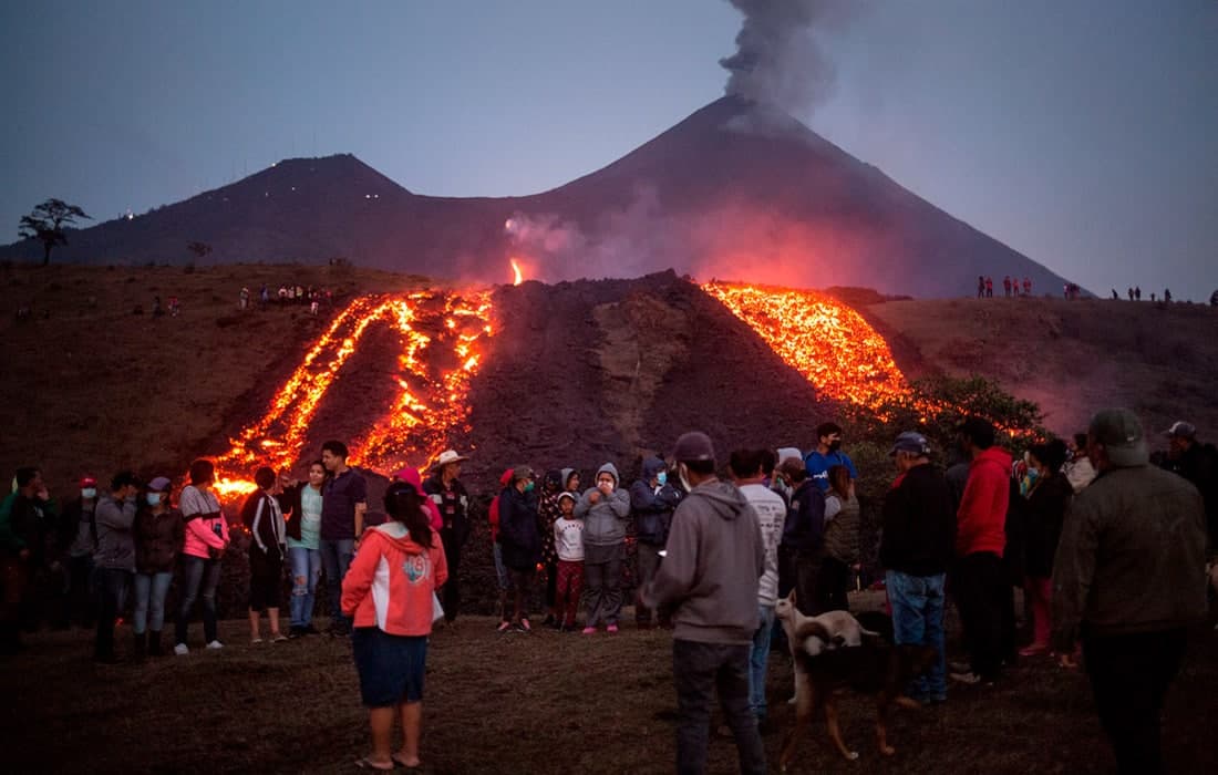 Gvatemalada harakatga kelgan Pakaya vulqonidan oqib tushayotgan lava yaqinida turgan odamlar.