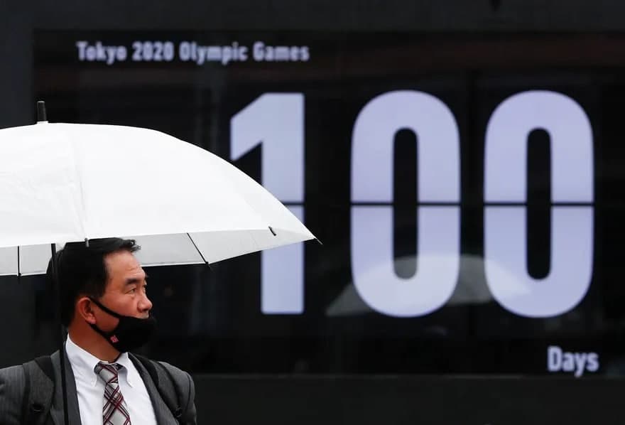 Японияда ўрнатилган Токио—2020 Олимпиадасига қанча кун қолганини кўрсатувчи табло олдида турган одам.
