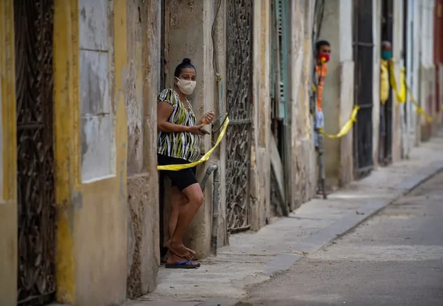 Куба пойтахти Гавана шаҳрида COVID-19 касаллиги аниқланганидан кейин одамлар тасмалар билан чегараланган ҳудуддаги уйларининг эшиги олдида туришибди. Мамлакат ҳукумати касаллик кўпайишини назорат қилиш учун янги чоралар эълон қилди.