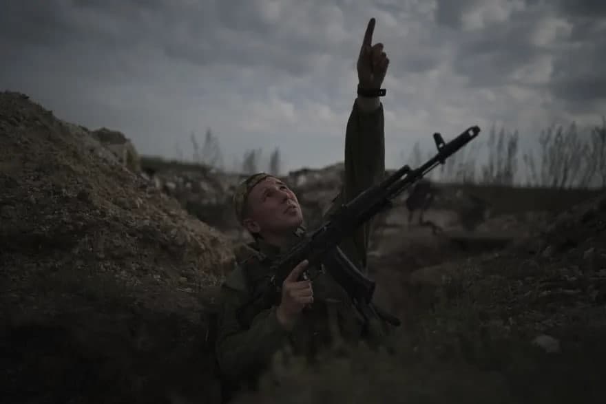 Donetsk yaqinida xandaqda turgan ukrain askari tepadan o‘tayotgan vertolyotga ishora qilmoqda.