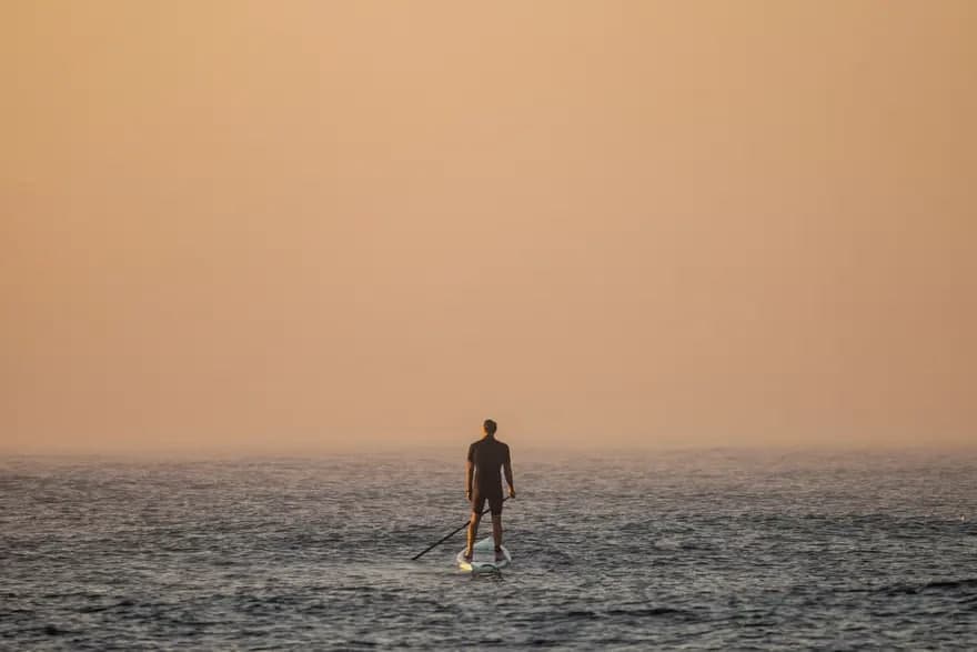 Туман қоплаган кўрфазда турган сёрфингчи. Австралияда дам олиш кунидаги жазирамадан кейин Марубра пляжини кучли туман қоплади.