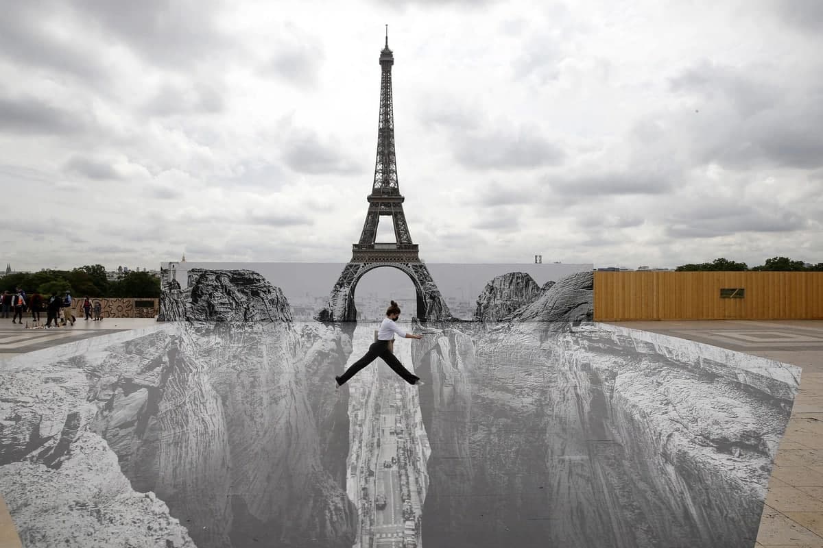 Француз фотографи ва кўча рассоми JR’нинг Парижда чизган арт-инсталляциясида суратга тушаётган аёл.