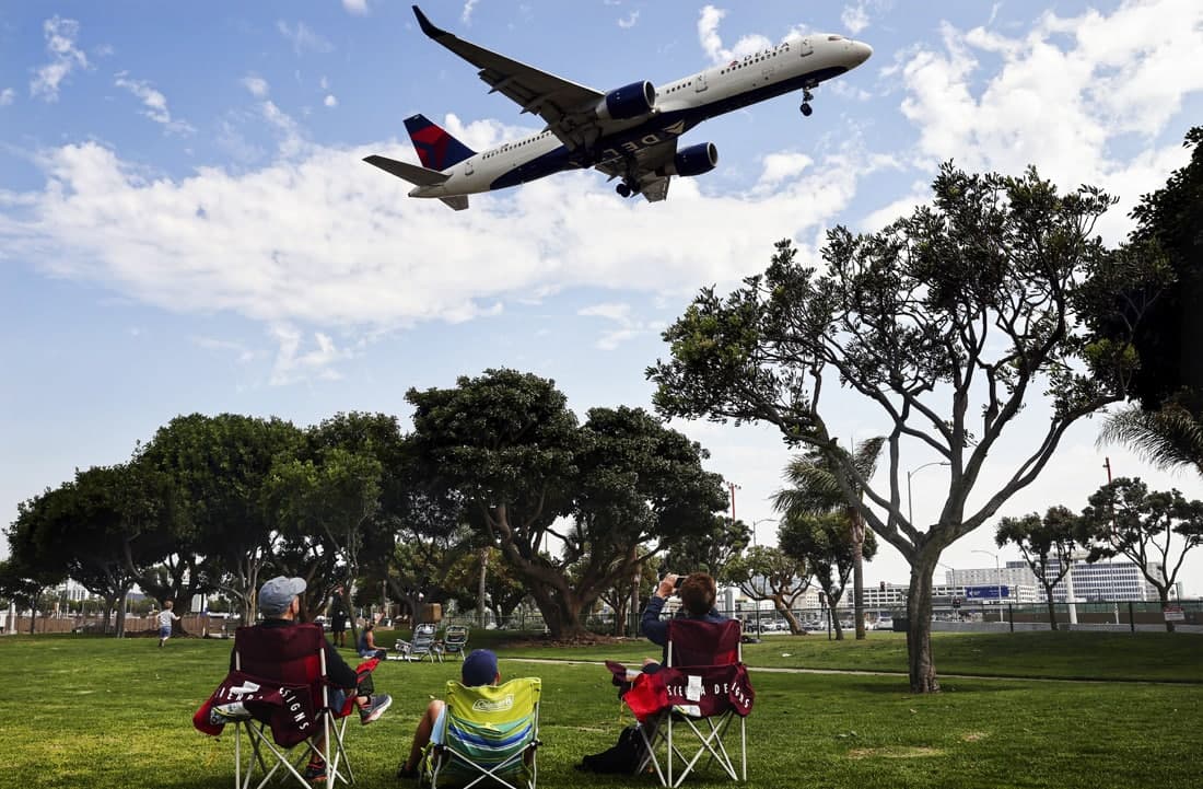 Bog‘dagi dam oluvchilar Delta Air Lines samolyotining Los-Anjeles aeroportiga qo‘nishini kuzatmoqda.