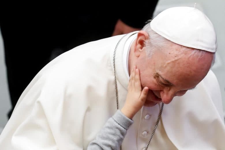 Vatikandagi haftalik audinsdan keyin Rim Papasi Fransiskning yuzini silayotgan bolaning qo‘li.