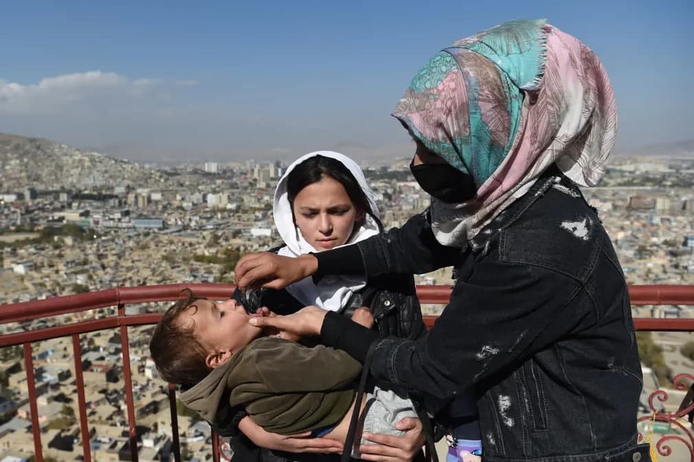 Тиббиёт ходими Кобулнинг эски кварталида эмлаш кампанияси чоғида болага полиомиелитга қарши вакцина томчиларини юбормоқда.