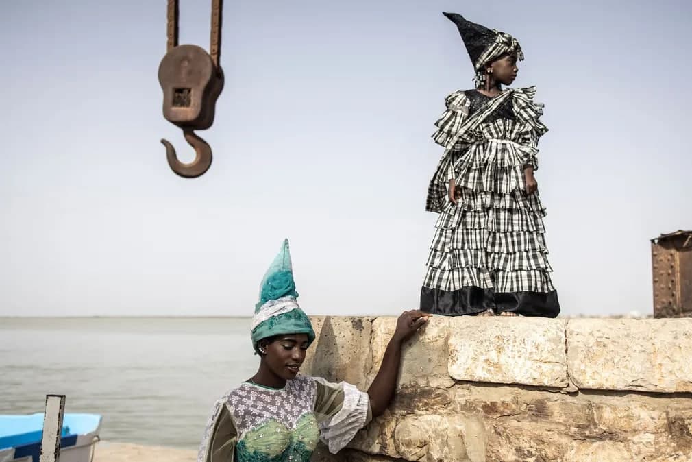 Сенегалда дизайнер Ндей Диоп Гуиссе билан ишлайдиган моделлар анъанавий Сигнар либосларида ташландиқ порт крани олдида суратга тушишди.
