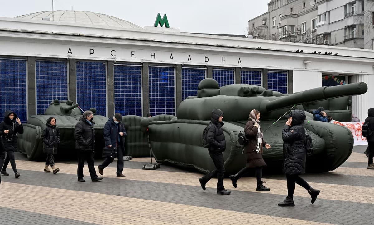 Украина пойтахти Киев шаҳридаги метро бекати яқинида ҳавода шиширилган танклар ёнидан ўтаётган одамлар.