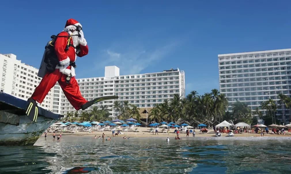 Санта Клаус Мексиканинг Герреро шаҳридаги Акапулко пляжида денгизга сакрамоқда.