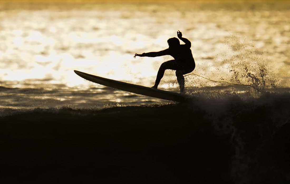 Калифорнияда сёрфинг билан шуғулланаётган сёрфер.