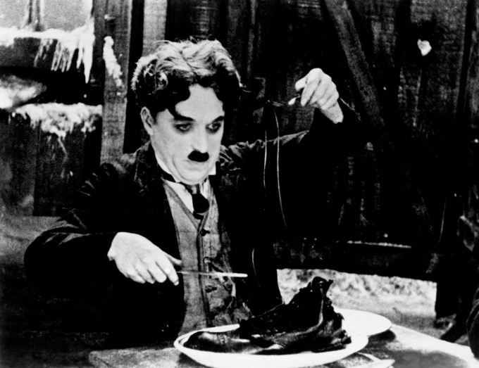 “Oltin vasvasasi” filmidan kadr (1952-yil). Sayoqning qoni shu qadar ochki, tuflisini yeb qo‘yadi – bog‘ichni sanchqiga spagetti kabi o‘rab, mixlarini suyakdek kemiradi. Bu sahna jahon kinosi tarixidagi eng mashhur sahnalardan biriga aylangan. Albatta, Chaplin suratga olish maydonchasida kino uchun qizilmiyadan maxsus tayyorlangan tuflini yegandi.