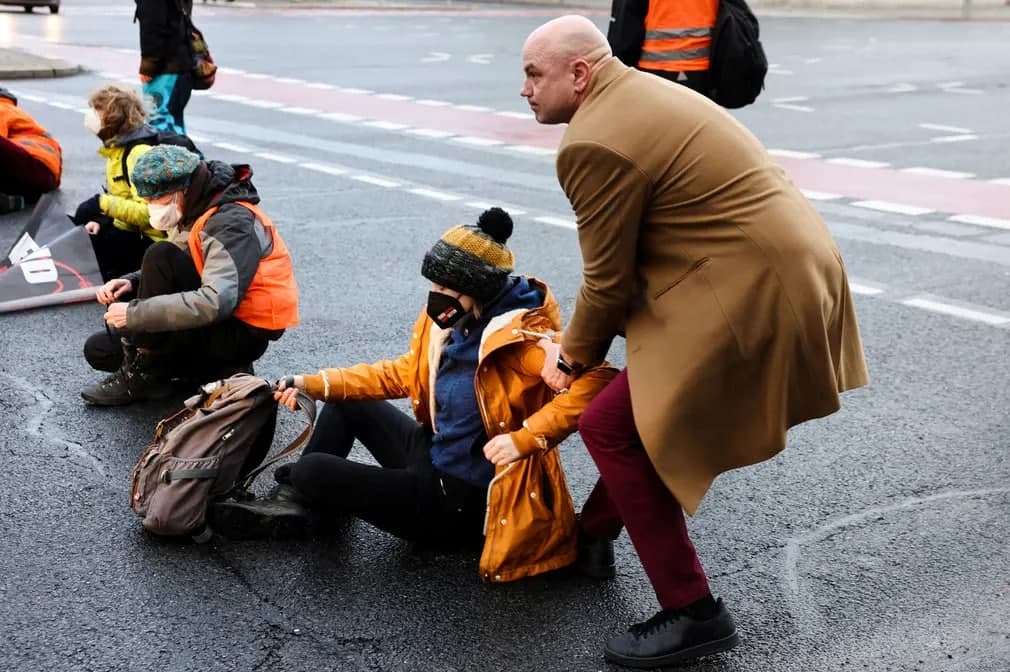 Berlinda avtomagistralni to‘sib qo‘ygan “So‘nggi avlod” faolini olib tashlashga urinayotgan erkak.