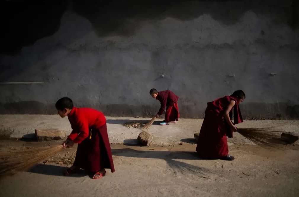 Yosh rohiblar Nepaldagi monastir tashqarisidagi piyodalar yo‘lagini supurmoqda.
