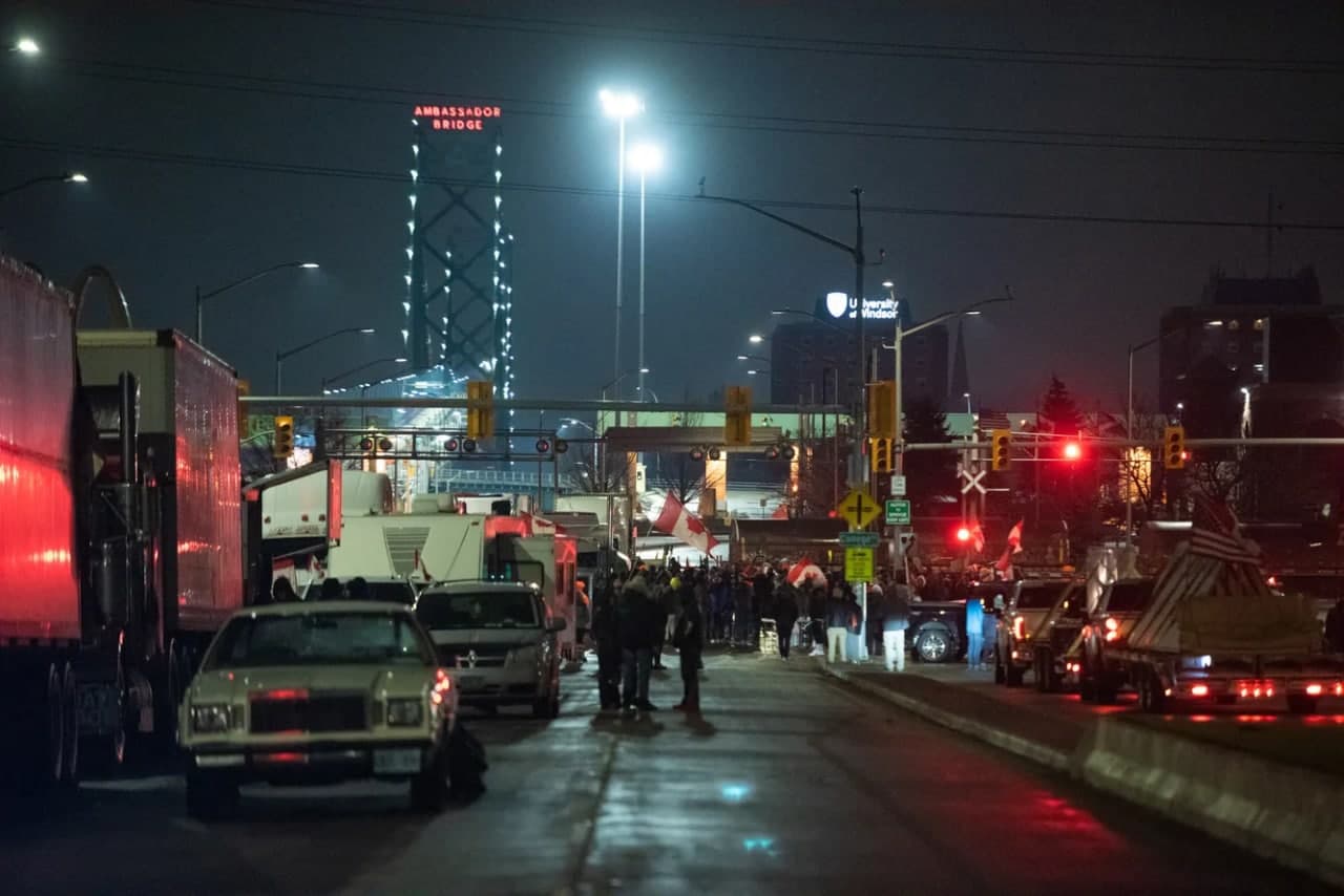 Намойишчилар Амбассадор кўприги (The Ambassador Bridge) устида ҳаракатланишни тўсиб қўймоқда. 2286 метрлик осма кўприк Детройт дарёси орқали Канаданинг Виндзор ва Американинг Детройт шаҳрини боғлайди. Автомобиль ишлаб чиқарувчилари кўприк блокадасидан азият чекмоқда: ушбу йўналишда одатда кунига 300 миллион долларлик товар ташилади, уларнинг учдан бир қисми автомобиль саноатига боғлиқ. Онтариодан Алабамагача жойлашган заводлардан айримлари ёпилишга мажбур бўлди. 11 февраль, 2022 йил.