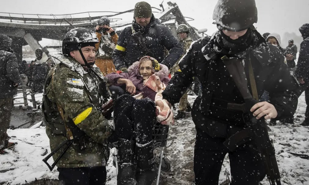 Ukrainalik harbiylar Irpindagi vayron bo‘lgan ko‘prik yaqinida keksa ayolni evakuatsiya qilmoqda.