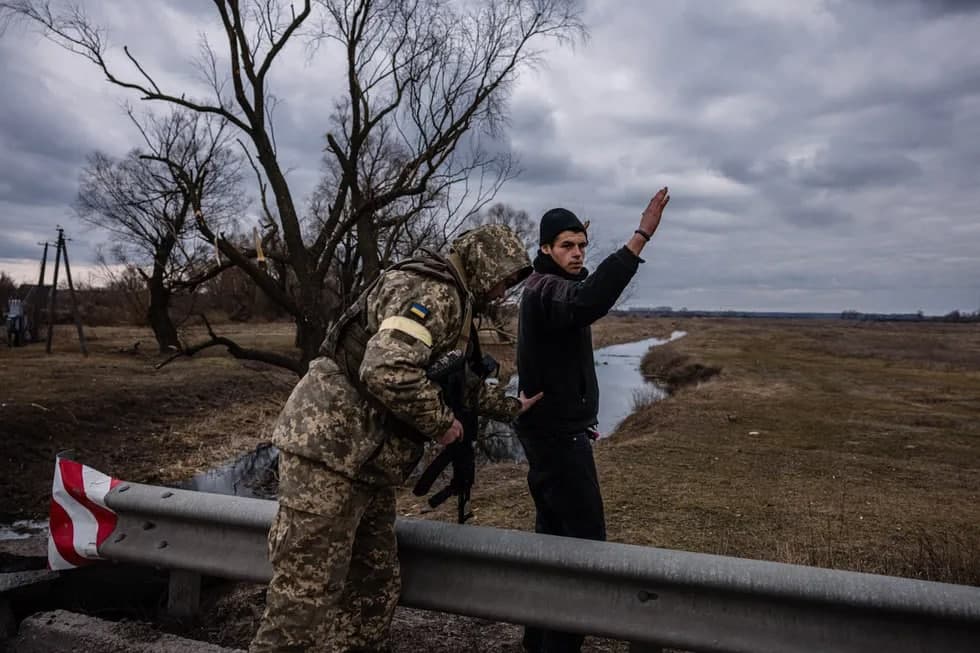 Ukraina askari Kiyev yaqinidagi Brovari shahri sharqidagi qishloqda erkakni tintuv qilmoqda