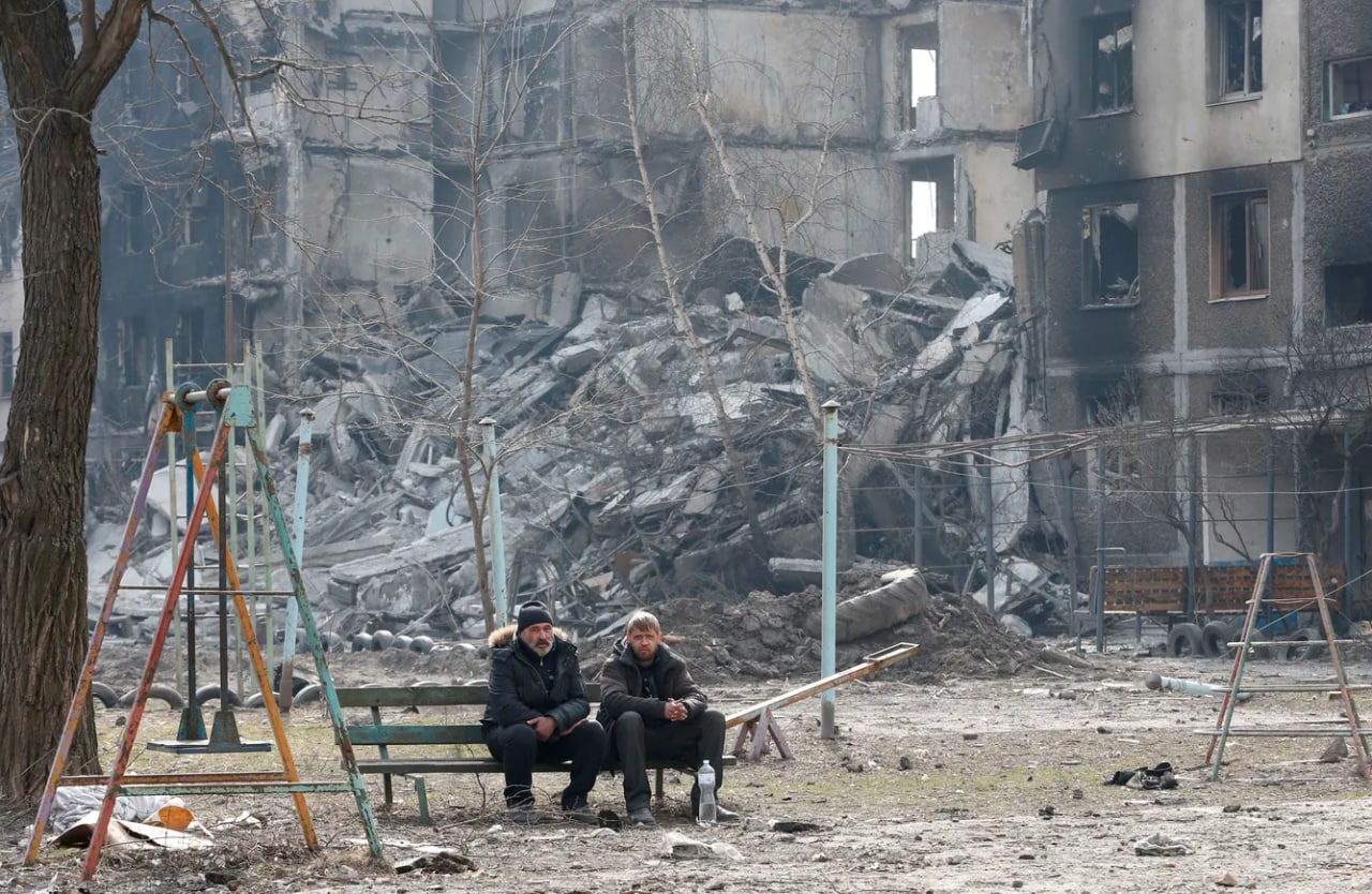 Mariupol aholisi vayron bo‘lgan uy yaqinidagi skameykada.