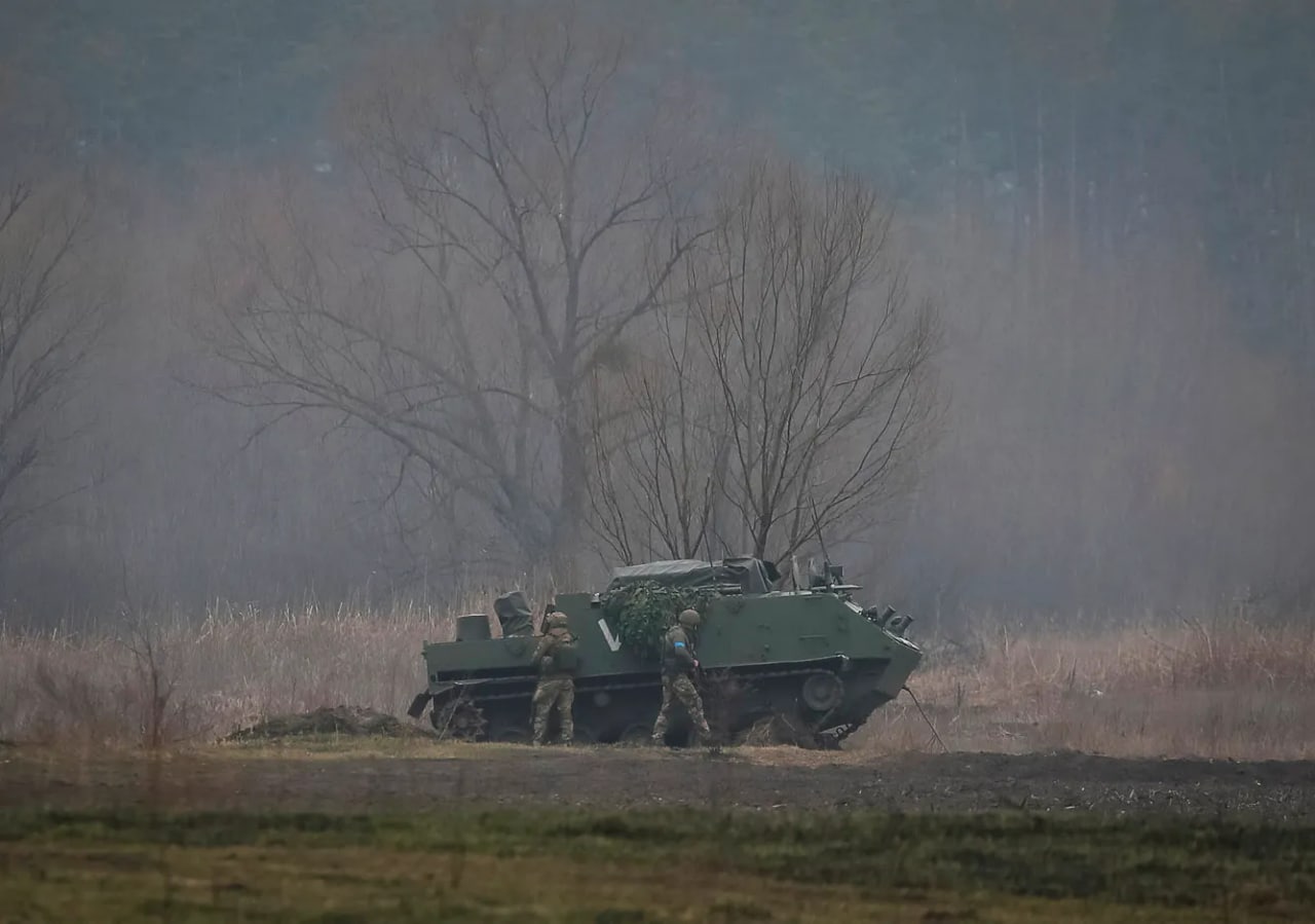 Kiyev yaqinidagi frontda rus zirhli transportyori yonida turgan ukrainalik askarlar.