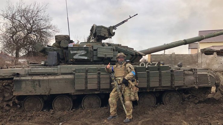 Ukrainalik askar ishdan chiqarilgan rus tanki yonida rasmga tushmoqda. 2022-yil