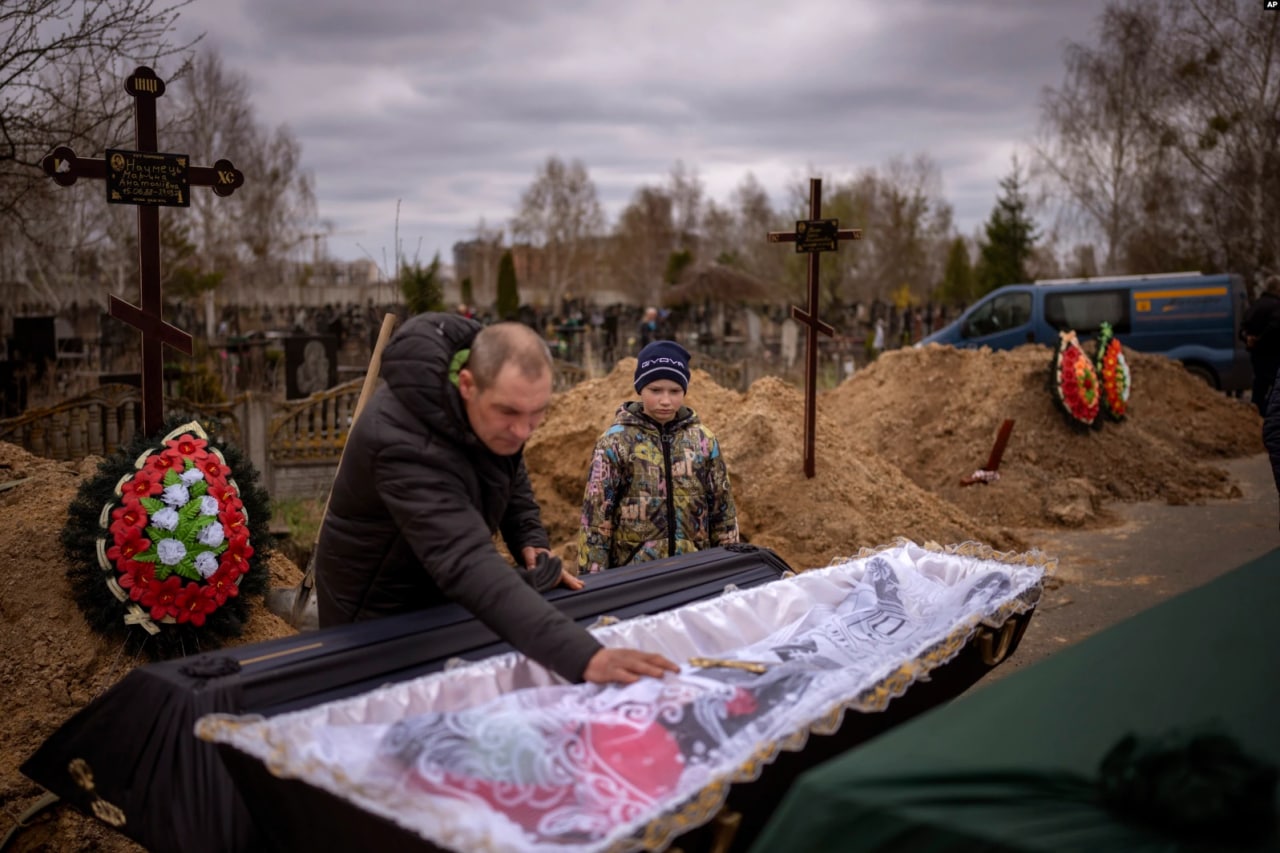 Buchadagi dafn marosimida tobutda yotgan onasi Marina bilan xayrlashayotgan 10 yoshli Vova va uning otasi Ivan Draxun.