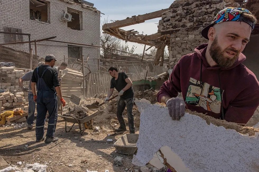 Mahalliy aholi Rossiya raketa zarbalarini berganidan keyin zarar ko‘rgan uy vayronalarini tozalamoqda