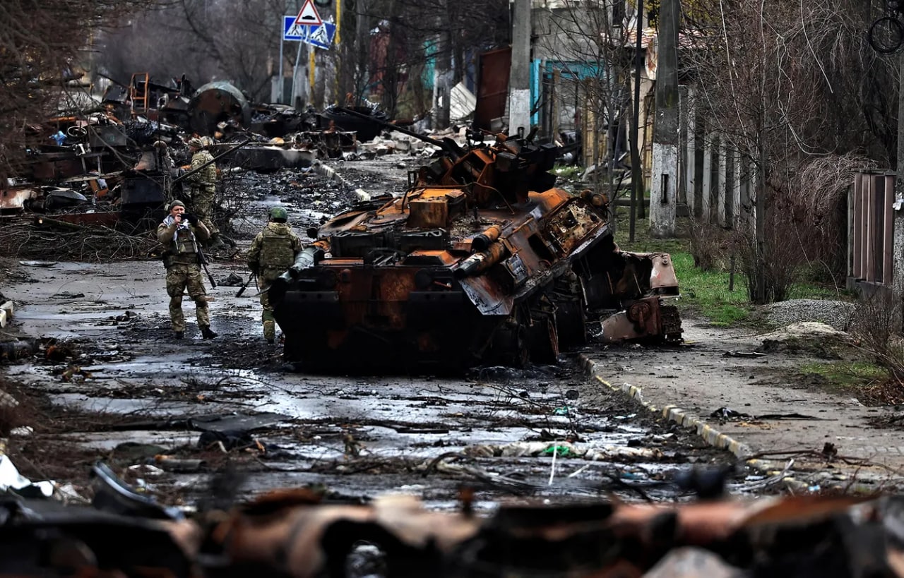 Ukrainalik askarlar vayron qilingan rus tanki yonida suratga tushmoqda. Bucha, Kiyev viloyati.