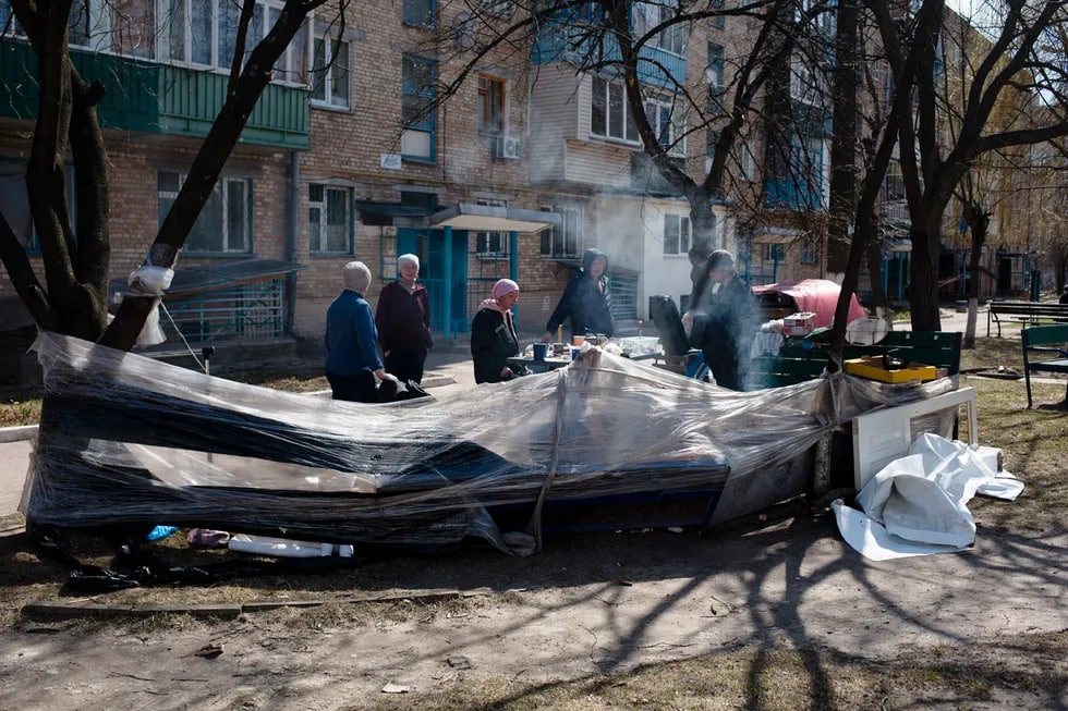 Буча аҳолиси кўп қаватли турар жой ҳовлисида оловда овқат пиширмоқда. Отишмалар сабабли шаҳар газ ва электрдан узилган.