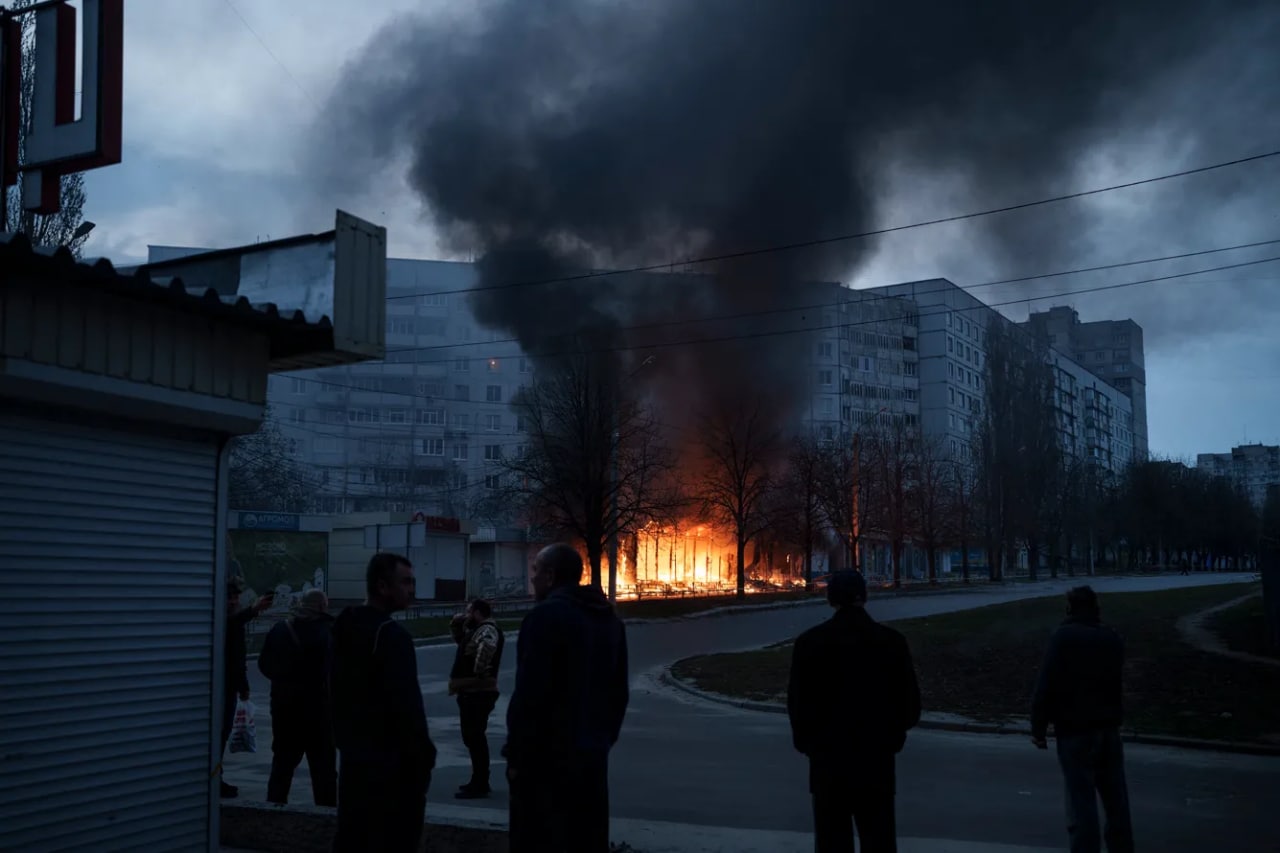 Харьковдаги кўп қаватли уй аҳолиси уй яқинида ўққа тутилиб, ёнаётган дўконларни кузатмоқда.