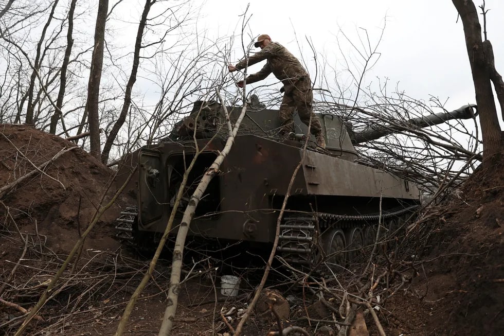 Lugansk g‘arbida ukrainalik artilleriyachi tank ustidan daraxt shoxlarini olib tashlamoqda.