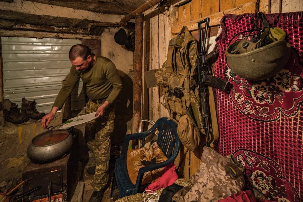 Ukrainalik askar yerto‘lada kechki ovqat tayyorlamoqda.