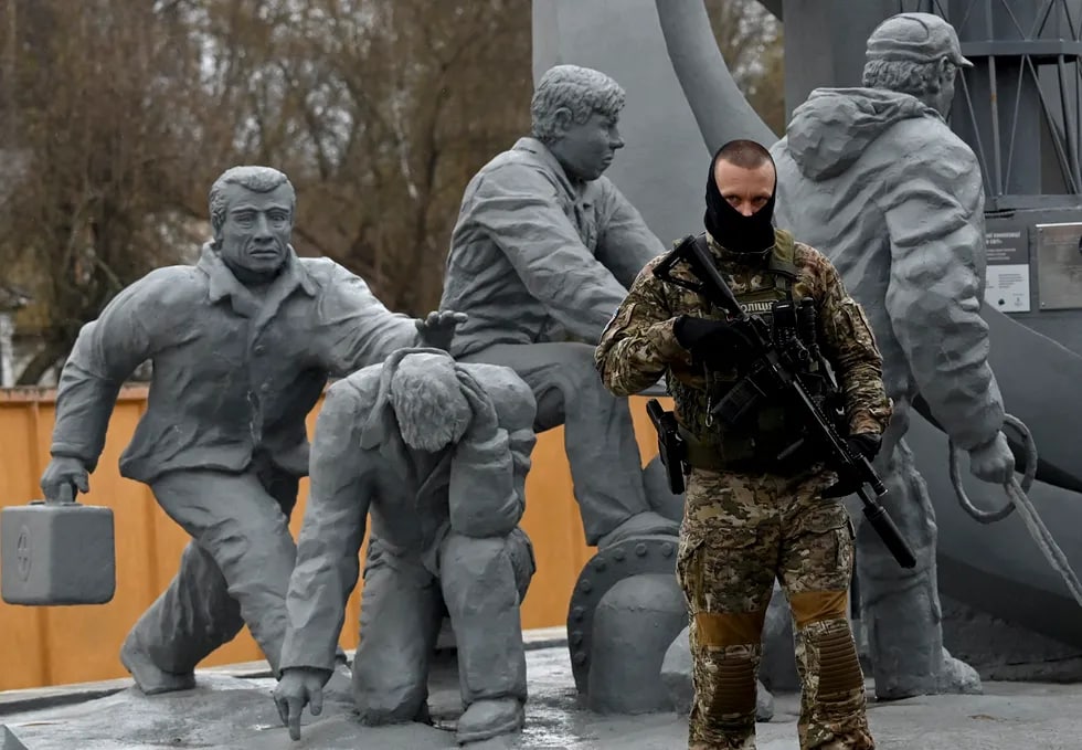 Ukrainalik askar Chernobil fojiasida halok bo‘lgan o‘t o‘chiruvchilarning haykallari oldida.
