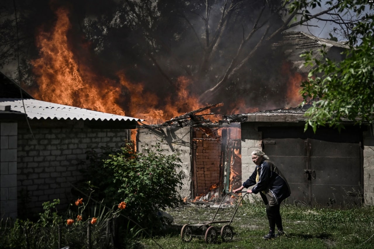 Ukraina sharqidagi Donbass viloyatidagi Lisichansk shahrida o‘qqa tutilganidan so‘ng yonayotgan garajdan uzoqlashayotgan keksa ayol.