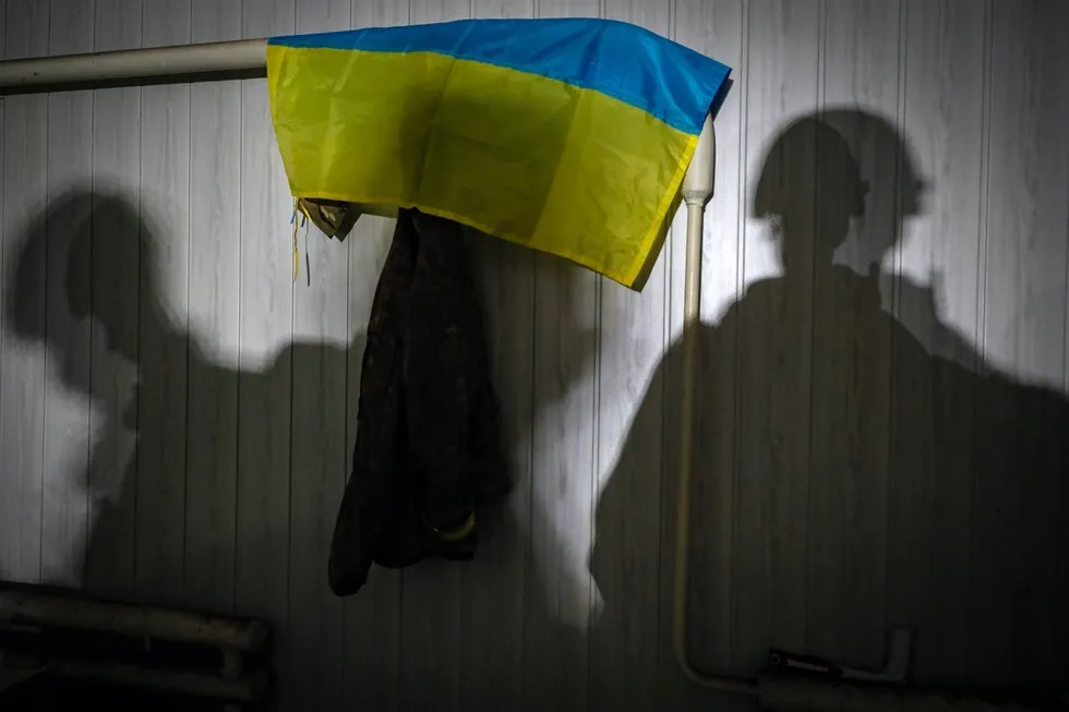 Мариуполдаги вайрон бўлган бункернинг Украина байроғи илинган деворига тушаётган россиялик ҳарбийлар соялари, 2022 йил 18 май