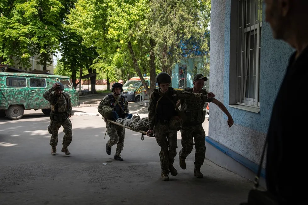 Ukraina harbiylari yarador quroldoshini olib kelmoqda, Donetsk viloyati.