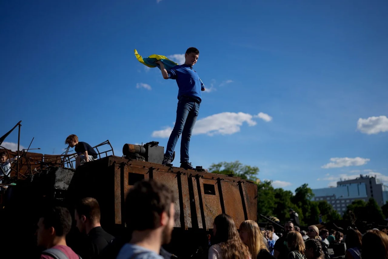 Kiyevlik yigit ishdan chiqarilgan rus tanki ustida Ukraina bayrog‘ini ko‘tarib turibdi.