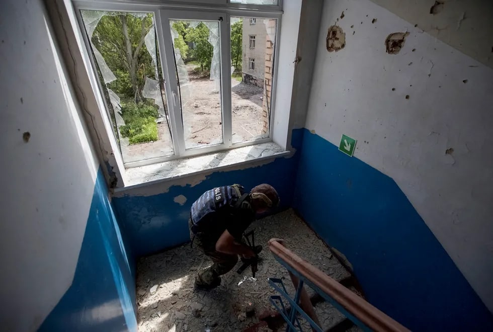 Ukraina politsiyasi Donetsk viloyatining Marinka shahridagi maktabda.Uning vazifasi — maktab binosida xavfsiz joyga evakuatsiya qilinishi kerak bo‘lgan mahalliy aholi bor-yo‘qligini tekshirish.