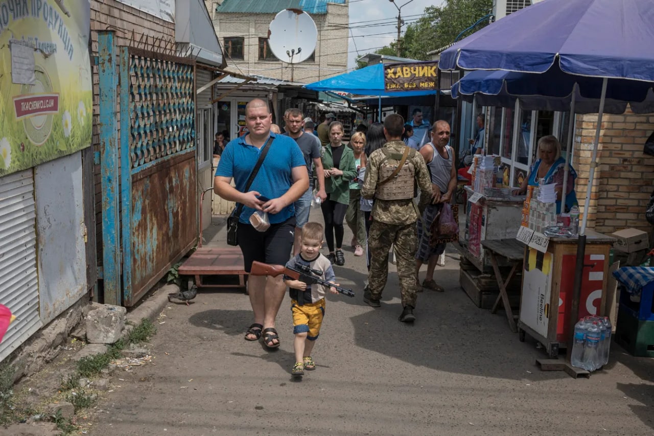 Donetsk viloyati Konstantinovka shaharchasidagi bozorda o‘yinchoq avtomat ko‘targan bolakay. Shahar ukrainaliklar nazoratida va Rossiya tomonidan muntazam o‘qqa tutilmoqda.