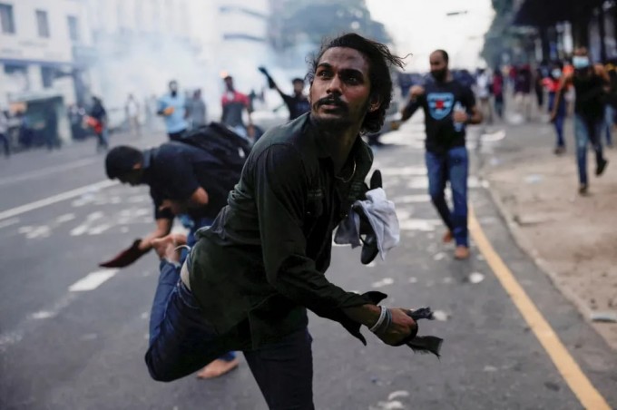 Kolombodagi namoyishchi politsiyaga qarshi ko‘zdan yosh oqizuvchi gaz granatasini uloqtirmoqda