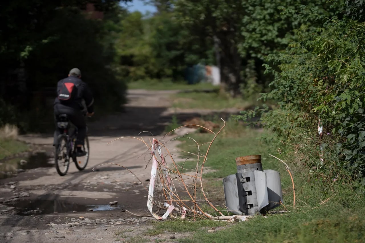 Велосипедчи Славянск турар жой массивида ерга тиқилиб қолган ракета ёнидан ўтмоқда.
