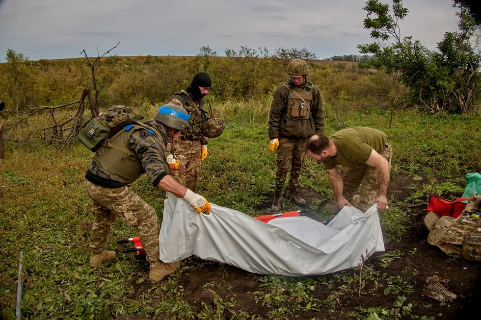 Ukrainalik harbiylar Dementyevka qishlog‘i yaqinida topilgan Ukraina Qurolli Kuchlari askarining jasadini ko‘tarib ketmoqda.
