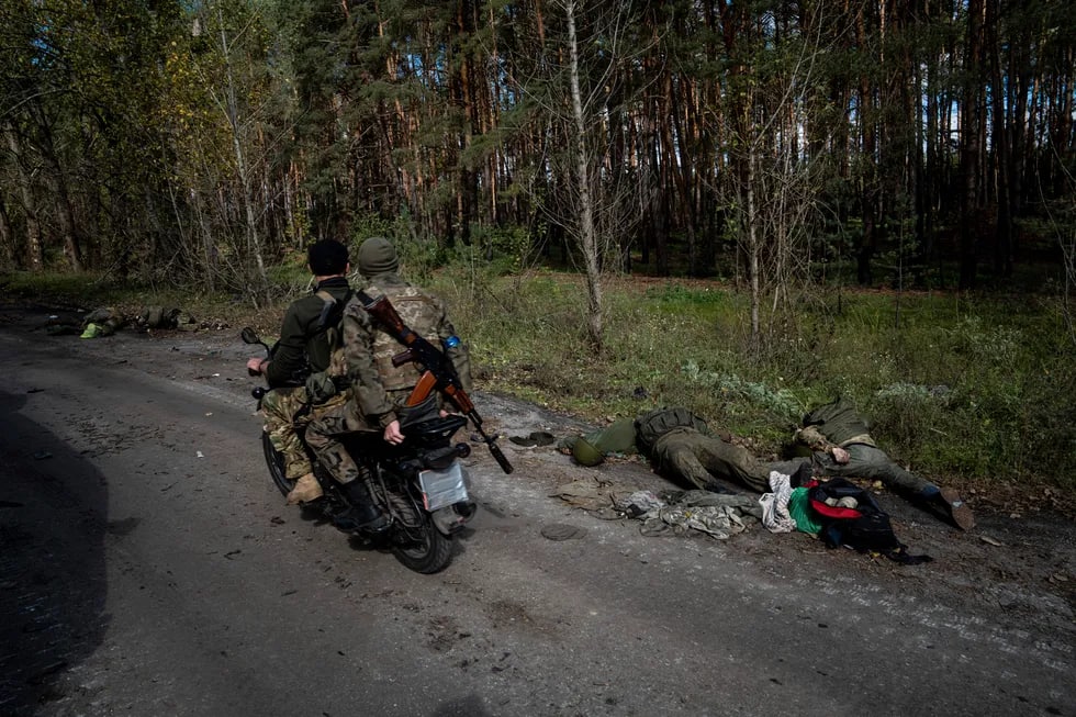 Ukraina Qurolli Kuchlari askarlari mopedda rus harbiylarining jasadlari yonidan o‘tmoqda.