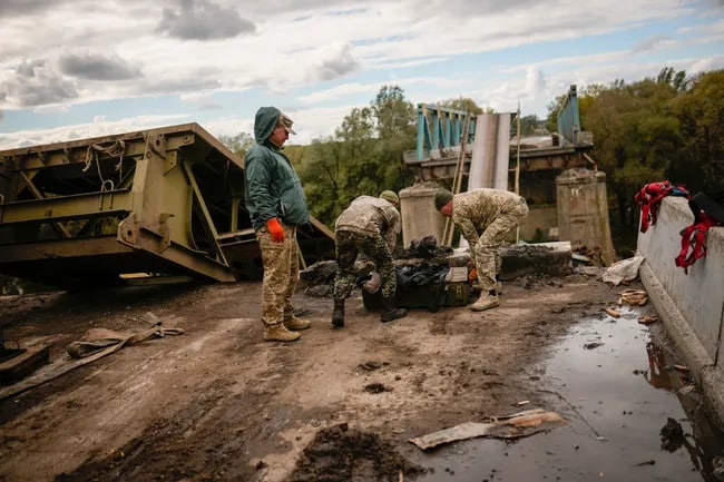 Ukraina askarlari ozod qilingan Izyumdagi ko‘prikdan metall bo‘laklarini yig‘ib olmoqda.