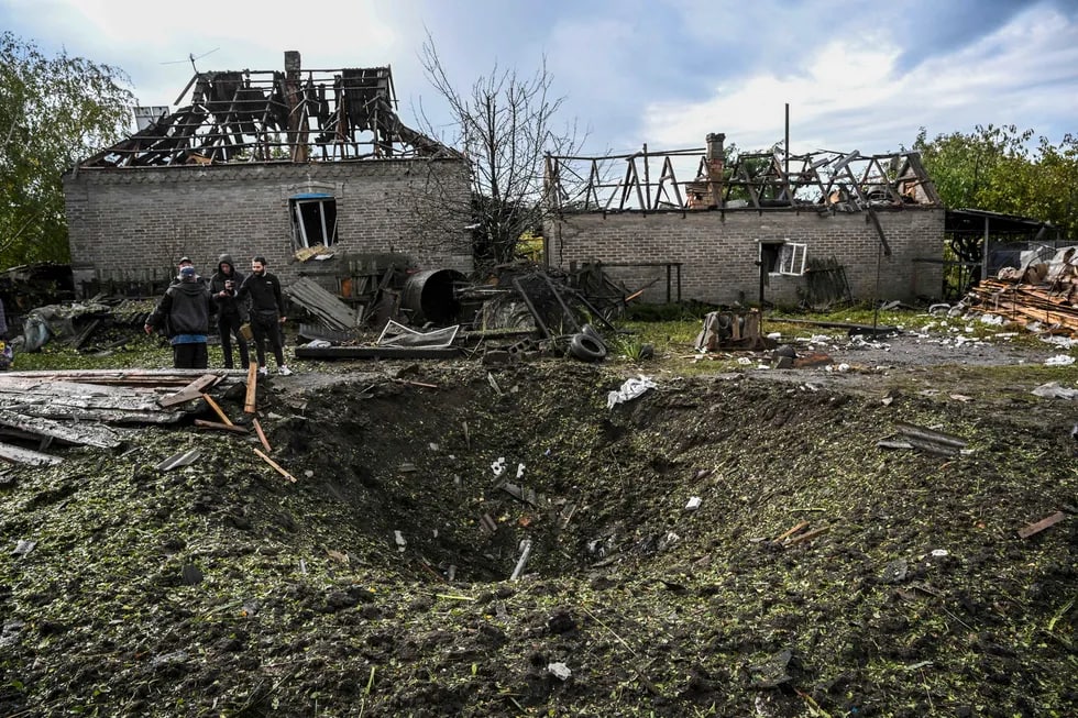 Donetsk viloyatining Kramatorsk shahri aholisi vayron bo‘lgan uy yonidagi o‘rani tomosha qilmoqda.