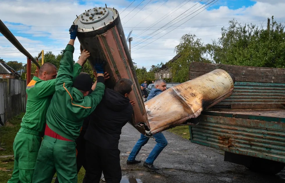Kommunal xizmatchilar Kramatorskda tungi hujumdan qolgan raketa korpusini yuk mashinasiga ortmoqda.