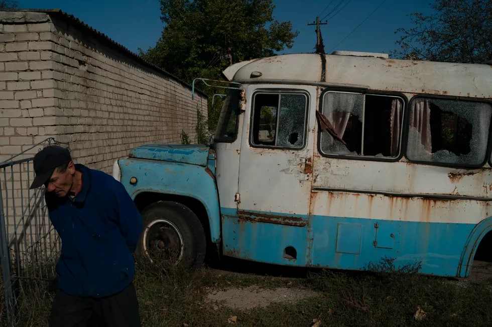 Bolshaya Aleksandrovkada mahalliy aholi vakili shikastlangan avtobus yonidan o‘tmoqda.
