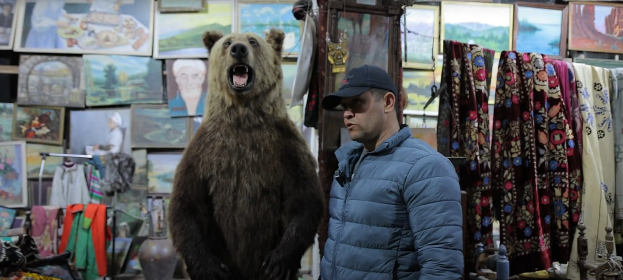 A mummified bear in an antique shop: A seller displays a stuffed bear among antiques and traditional fabrics, Yangiabad Bazaar, Tashkent, Uzbekistan, November 2024  Photo: Daryo